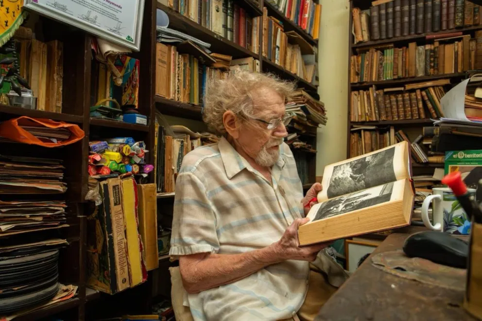 Ricardo Raymondo, librero y sabio de la literatura, cuando su salud se lo permite, se sienta en el mostrador de La Palma. Ahora, para poder hacerlo, requiere una mochila de oxígeno trasladable. Fotos: Agustina Vera  